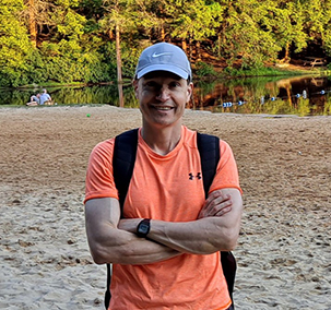 Image of Dr. Konstantin Getman in front of a lake with woods in the background.